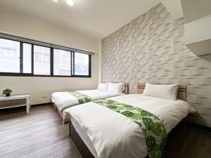 2 camas en una habitación con una pared de ladrillo en 長月居 en Taichung