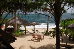a beach with chairs and umbrellas and the ocean at Ibisbird Beach Bungalow in Tangalle