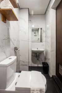 a white bathroom with a toilet and a sink at Airo Hotel Manila in Manila