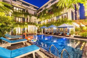 an image of a hotel pool with chairs and umbrellas at SHALA BOUTIQUE HOIAN in An Bang