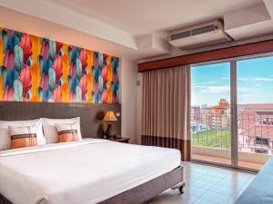 - une chambre avec un grand lit et une grande fenêtre dans l'établissement Piyada Residence Pattaya, à Pattaya (sud)