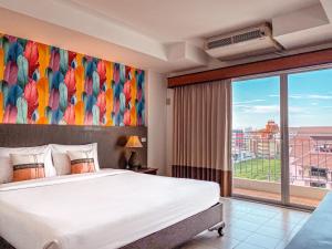 a hotel room with a bed and a window at Piyada Residence Pattaya in Pattaya South