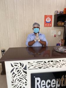 une personne portant un masque assise à une table dans l'établissement Hotel Gopal, à Haridwar