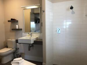 a bathroom with a toilet, sink, and mirror at Saltair Luxury Accommodation - Adults Only in Albany