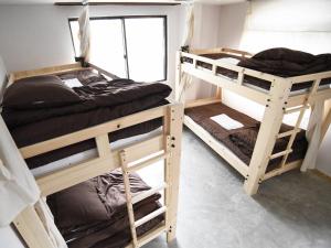 a room with three bunk beds and a window at Bacchus Kofu Guesthouse in Kofu