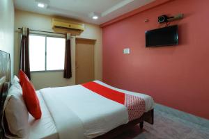 a bedroom with a red wall with a bed and a television at Jaya Krishna Mansions in Vellore