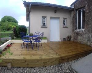 una terraza de madera frente a una casa con mesa y sillas en L Atelier Demoiselle, en Cadillac