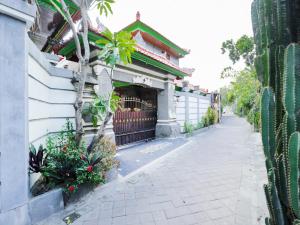 a fence next to a building with plants and a sidewalk at OYO 4003 Ceria Guesthouse Seminyak in Seminyak