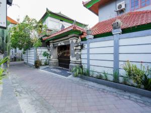 a white house with a red roof and a sidewalk at OYO 4003 Ceria Guesthouse Seminyak in Seminyak