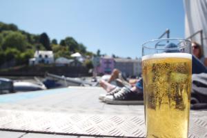 a glass of beer sitting on a table with people at St Elmo House in Dartmouth