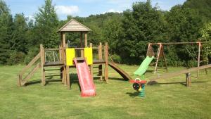 un parque infantil de madera con tobogán y cenador en La Clé des Champs, en Bertogne