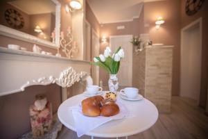 a table with two pastries and a vase with flowers at Domus Mariae B&B Assisi in Assisi
