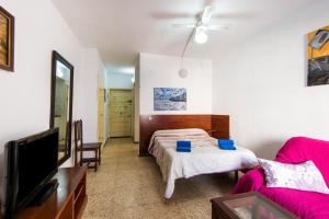 una camera con letto, TV e divano di Apartamento Pino Torremolinos a Torremolinos