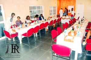a group of people sitting at a long table with red chairs at Residence Ivoire Cotonou in Cotonou