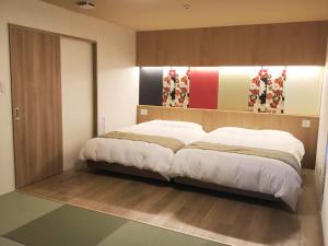 a bedroom with a large bed with white sheets at Kyoto Central Inn in Kyoto