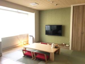 a living room with a table and a television on a wall at Kyoto Central Inn in Kyoto