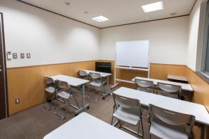 a classroom with tables and chairs and a whiteboard at Kyoto Central Inn in Kyoto