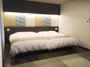 a bedroom with a large bed with white sheets at Kyoto Central Inn in Kyoto