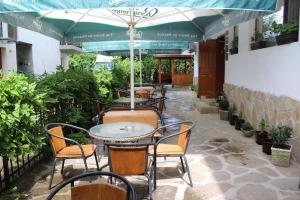 un patio al aire libre con mesas, sillas y sombrillas en Family Hotel Biju en Tryavna