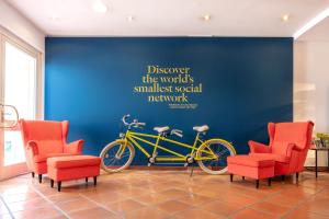 una bicicletta gialla parcheggiata contro un muro blu con sedie rosse di Golden Tulip Luebecker Hof a Lubecca