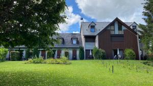 une grande maison avec une cour verdoyante plantée d'arbres dans l'établissement Logis Auberge du Barrez, à Mur-de-Barrez