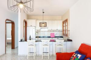 una cocina con armarios blancos y un bar con taburetes en Salitre, en Playa Honda