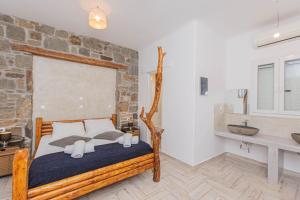 a bedroom with a wooden bed and a stone wall at Bebis House in Klouvas