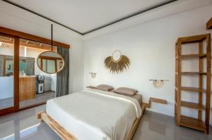 a white bedroom with a bed and a mirror at Kiki Village Private Villas in Canggu