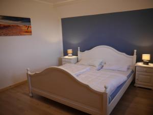 ein Schlafzimmer mit einem weißen Bett und zwei Nachttischen in der Unterkunft Ferienhaus am Nordseedeich in Alleinlage in Hooksiel