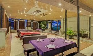 um restaurante com mesas roxas, cadeiras e plantas em Treebo Trend Sai Samrat Resort Satara em Satara