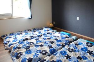 Bett in einem Schlafzimmer mit einer blauen und weißen Bettdecke in der Unterkunft 石垣島北部一棟貸しコテージあちみぃん（achimiin） in Ishigaki-jima
