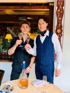 zwei Männer mit Weingläsern stehen neben einem Tisch in der Unterkunft Hotel Salvan in Campitello di Fassa