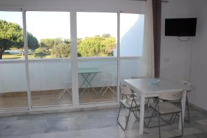 チクラナ・デ・ラ・フロンテーラにあるApartamento Retama Golf IIの白いテーブルと椅子、窓が備わる客室です。