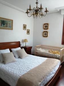 Un dormitorio con una cama con sábanas blancas y una lámpara de araña. en Tres Fuentes Turismo, en Valgañón