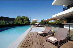 a swimming pool with two chairs and a table next to it at Crowne Plaza Montpellier Corum, an IHG Hotel in Montpellier