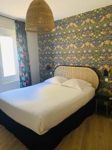 un letto in una camera da letto con parete floreale di Hôtel Central ad Avignone