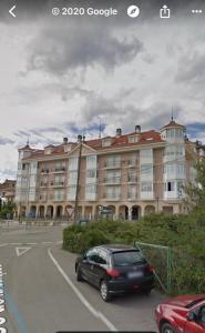 czarny samochód zaparkowany przed dużym budynkiem w obiekcie Ermita San Vicente de la Barquera Duplex w mieście San Vicente de la Barquera