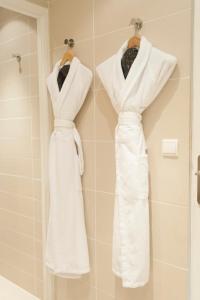 two white wedding dresses hanging on a rack in a bathroom at Du C&ocirc;t&eacute; Des Olivades in Paradou