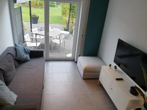 a living room with a couch and a tv and a patio at Le Berc'AYE in Aye