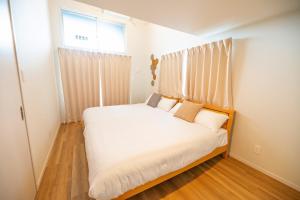 1 dormitorio con 1 cama con sábanas blancas y ventana en Hotel Tomas Asahibashi Station en Naha