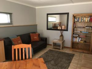 uma sala de estar com um sofá preto e um espelho em African Dawn B&B em Calvinia