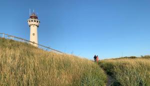 a lighthouse on a hill with a person walking up the hill at Jagershof in Egmond aan den Hoef