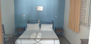 a bed in a blue room with two white pillows at Apostolakis Rooms in Agios Kirykos