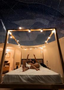 two women laying on a bed with their hands in the air at Ursa Major Bubble in Camporgiano