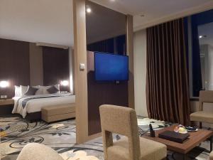 um quarto de hotel com uma cama e uma televisão de ecrã plano em ASTON Gorontalo Hotel & Villas em Gorontalo