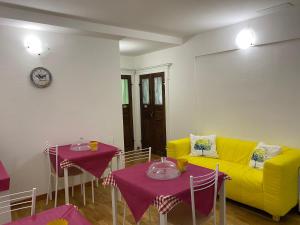 un soggiorno con divano giallo e 2 tavoli di B&B DORMIRE DAI GRIMALDI a Genova
