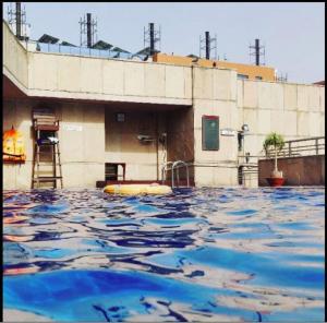 einem Pool mit blauem Wasser vor einem Gebäude in der Unterkunft Fortune Select Global, Gurugram - Member ITC's Hotel Group in Gurgaon