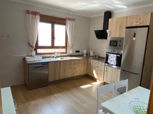 una cucina con frigorifero in acciaio inox e mobili in legno di Chalet con piscina privada de 4 dormitorios Las Herrerias -cerca de Vera Playa- a Cuevas del Almanzora