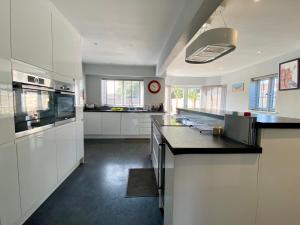 uma grande cozinha com armários brancos e bancadas pretas em Southernwood - Wantage Road House em Didcot