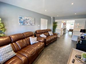 a living room with a brown leather couch at Southernwood - Wantage Road House in Didcot